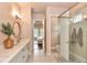 Elegant bathroom with double vanity, round mirror, and glass-enclosed shower adjacent to a doorway at 604 Mosaic Blvd, Daytona Beach, FL 32124