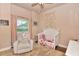 Bedroom with a white crib, a comfortable chair and soft, neutral decor at 604 Mosaic Blvd, Daytona Beach, FL 32124