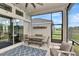 Cozy screened patio with dining set, blue outdoor rug, and a view of the backyard and pond at 604 Mosaic Blvd, Daytona Beach, FL 32124