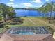 Lush backyard featuring a screened pool and a scenic lake view beyond the well-manicured lawn at 22527 Lake Seneca Rd, Eustis, FL 32736