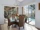 Bright dining area featuring a glass table, cushioned wicker chairs, and sliding glass doors to the screened-in patio and pool at 22527 Lake Seneca Rd, Eustis, FL 32736