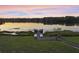 Picturesque sunset view over the lake, featuring a wooden dock with seating and tranquil water reflections at 22527 Lake Seneca Rd, Eustis, FL 32736