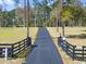 View of the long private driveway featuring an entrance gate, mature trees and lush grassy area at 22527 Lake Seneca Rd, Eustis, FL 32736