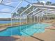 The screened-in pool boasts a sparkling, clear blue, inviting swimming and is surrounded by lush greenery at 22527 Lake Seneca Rd, Eustis, FL 32736