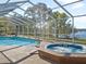 Screened pool and hot tub overlook tranquil lake, offering a serene retreat, surrounded by lush landscaping and sunny skies at 22527 Lake Seneca Rd, Eustis, FL 32736