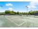 Outdoor tennis court surrounded by mature trees and bright blue skies on a sunny day at 3428 Rexford Cir, Ormond Beach, FL 32174