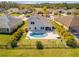 Aerial view of a backyard featuring a kidney-shaped pool, patio area, and manicured landscaping enclosed by a wrought iron fence at 225 Perfect Dr, Daytona Beach, FL 32124