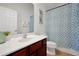 Well-lit bathroom with a wood vanity, white sink, patterned shower curtain, and tiled floor at 410 Viola Dr, Davenport, FL 33837