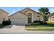 Beautifully landscaped single-story home with a red tile roof, two-car garage and mature palm tree at 410 Viola Dr, Davenport, FL 33837