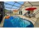 Screened in pool area with lounge chairs, outdoor seating and a vibrant red umbrella at 410 Viola Dr, Davenport, FL 33837