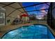 This screened-in pool is surrounded by lounge furniture and overlooks a treed yard at 410 Viola Dr, Davenport, FL 33837