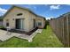 Backyard featuring a patio area with a table and chairs, grassy lawn, and wooden privacy fence at 105 Cattail Ct, Kissimmee, FL 34743