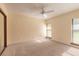 Bright bedroom featuring windows with backyard views, a ceiling fan, and neutral-toned walls at 206 Sage Brush Trl, Ormond Beach, FL 32174