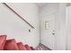 Entryway featuring a white front door with decorative glass and red carpeted stairs with a wooden handrail at 322 Garden St, Daytona Beach, FL 32114