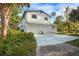 White two-story home featuring a two-car garage, tropical foliage, and a wide concrete driveway at 322 Garden St, Daytona Beach, FL 32114
