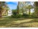 View of a two-story home with a two car garage from behind a green lawn and numerous trees at 322 Garden St, Daytona Beach, FL 32114