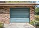 Attached one car garage with a teal door and brick siding at 3385 Ne 44Th Pl, Ocala, FL 34479