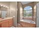 Bathroom featuring a soaking tub with tile surround, double vanity, and natural light at 39601 Harbor Hills Blvd, Lady Lake, FL 32159