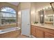 Luxurious bathroom with a soaking tub under a large window, vanity, and tile flooring at 39601 Harbor Hills Blvd, Lady Lake, FL 32159