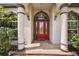 Close-up of the entryway, showcasing a red front door framed by elegant columns and arched windows at 39601 Harbor Hills Blvd, Lady Lake, FL 32159