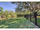 Scenic backyard view with lush green grass, a pond, and a secure black fence at 6172 Knotty Pine Ct, Port Orange, FL 32127