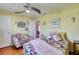 Inviting bedroom with bright yellow walls, a ceiling fan, and a colorful floral patterned bedspread at 6172 Knotty Pine Ct, Port Orange, FL 32127
