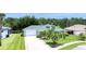 Well-maintained single-story home showcasing a long driveway, mature palm trees, and a neatly landscaped yard at 6172 Knotty Pine Ct, Port Orange, FL 32127