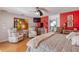 Bright bedroom with red accent wall, hardwood floors, sitting area, ensuite bathroom, and ceiling fan at 6172 Knotty Pine Ct, Port Orange, FL 32127