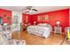 Spacious main bedroom with red accent wall, hardwood floors, ensuite bathroom, and ceiling fan at 6172 Knotty Pine Ct, Port Orange, FL 32127