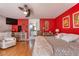 Bright bedroom with red accent wall, hardwood floors, ensuite bathroom, and ceiling fan at 6172 Knotty Pine Ct, Port Orange, FL 32127