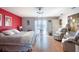 Bright bedroom with red accent wall, hardwood floors, sitting area, and ceiling fan at 6172 Knotty Pine Ct, Port Orange, FL 32127