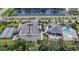 Aerial shot of a community with a pool, tennis courts, a clubhouse and ample parking surrounded by trees at 1010 Megano Blvd, Deland, FL 32724