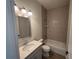 Bright bathroom featuring a shower over tub, chrome fixtures, light gray vanity and gray tiled walls at 1010 Megano Blvd, Deland, FL 32724