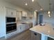 Well-equipped kitchen featuring a microwave, electric cooktop, tile backsplash, and quartz countertop at 1010 Megano Blvd, Deland, FL 32724