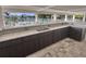 Outdoor kitchen area featuring sleek cabinetry, granite countertops, a sink, and a view of the pool area at 1010 Megano Blvd, Deland, FL 32724