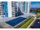 Aerial view of community tennis court and building, with a glimpse of water in the background at 925 N Halifax Ave # 1105, Daytona Beach, FL 32118