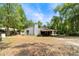 The backyard is covered with dried leaves with a covered patio at 230 Katrina St # 230, De Leon Springs, FL 32130
