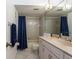 Well-lit bathroom featuring a vanity with sink and a shower-tub combo with blue curtain at 1 Tomoka Oaks Blvd # 102, Ormond Beach, FL 32174
