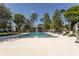 Large community swimming pool with lounge chairs and tables, and lush landscaping around the area at 1 Tomoka Oaks Blvd # 102, Ormond Beach, FL 32174