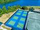 Aerial view of tennis courts with green and blue surfaces, surrounded by lush vegetation at 1128 Hansberry Ct, Ormond Beach, FL 32174