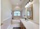 Bright bathroom with a tub-shower combo, vanity with a white countertop, decorative mirror and tiled floor at 1404 Newry Cir, Ormond Beach, FL 32174