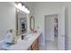 Well-lit bathroom featuring a white counter, decorative mirror, and doorways leading to other rooms at 1404 Newry Cir, Ormond Beach, FL 32174