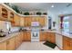 Bright kitchen featuring light wood cabinetry, lots of counter space, and white appliances at 1404 Newry Cir, Ormond Beach, FL 32174
