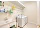 Functional laundry room with a utility sink, washer, dryer and plenty of storage shelves at 1404 Newry Cir, Ormond Beach, FL 32174