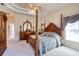 Spacious primary bedroom featuring a four-poster bed, dresser, and carpeted floors at 1404 Newry Cir, Ormond Beach, FL 32174