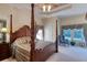 Elegant primary bedroom with a four-poster bed, tray ceiling, and a sitting area by a window at 1404 Newry Cir, Ormond Beach, FL 32174