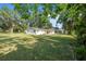 View of the spacious backyard with lush green grass and mature trees, perfect for outdoor activities at 2120 Queen Palm Dr, Edgewater, FL 32141