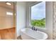 Bright bathroom featuring a free-standing tub and walk-in shower overlooking lush landscaping at 32 Ocean Breeze Cir, Ormond Beach, FL 32176
