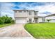 Two-story home shows neutral colors, a brick driveway, and green lawn at 32 Ocean Breeze Cir, Ormond Beach, FL 32176