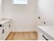 Bright laundry room with white cabinets, marble countertops, and wood-look floors at 32 Ocean Breeze Cir, Ormond Beach, FL 32176